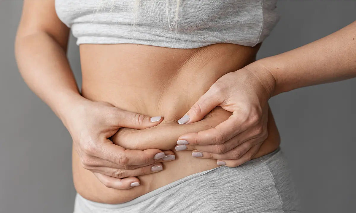 Pessoa segurando a região abdominal, evidenciando retenção de líquidos ou inchaço na barriga.